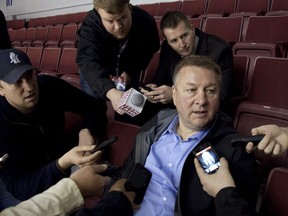 Former Vancouver Canucks General Manager Mike Gillis, centre, takes questions from reporters in 2011.