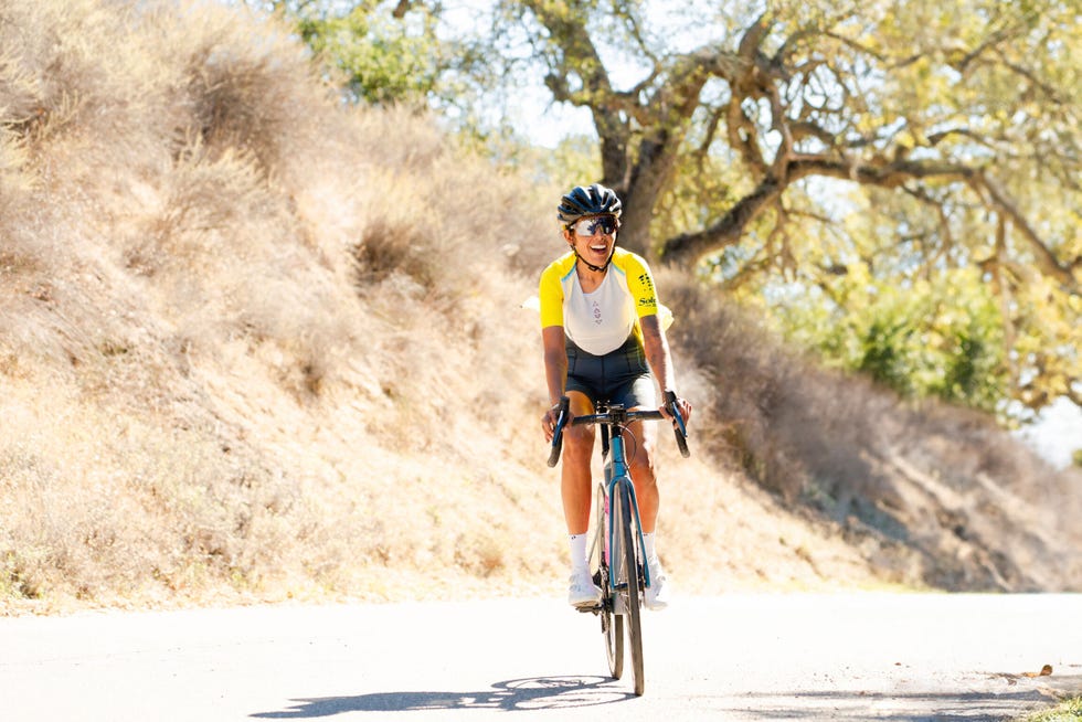 Cyclist riding on a road surrounded by dry vegetation. Cyclist riding on a road surrounded by dry vegetation.