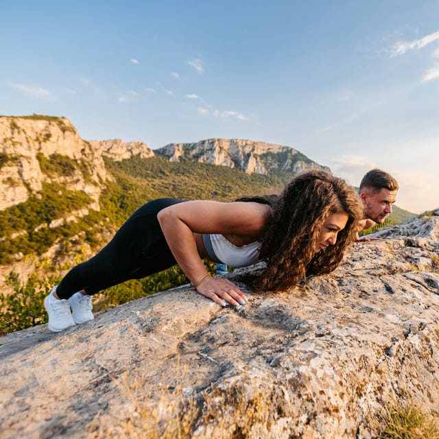 Young Couple Doing Push-Ups On Top Of The Mountain Young Couple Doing Push-Ups On Top Of The Mountain