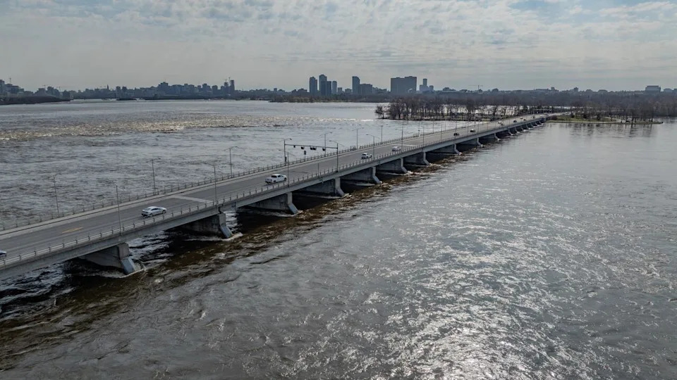 Vehicles drive along the Chaudière Bridge on April 22, 2026 as the water along the Ottawa River flows high underneath.