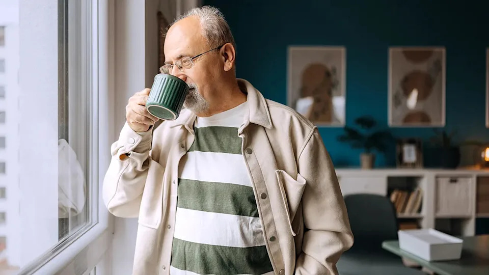 Senior man drinking coffee and looking out a window