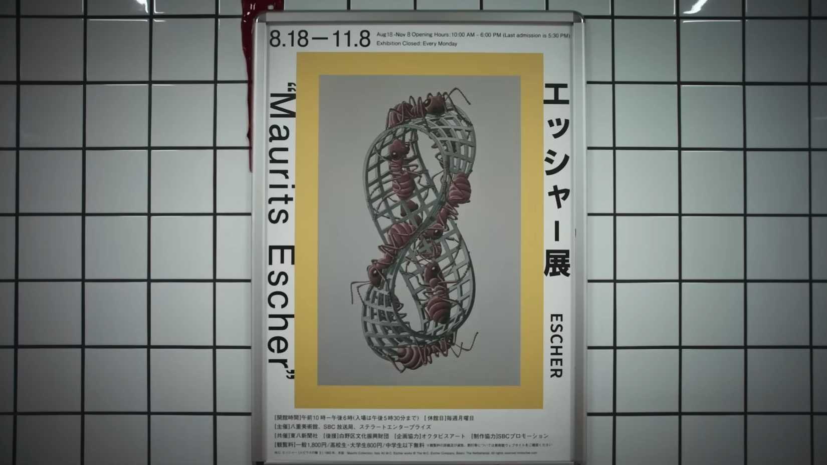 A screenshot from the Exit 8 trailer showing one of the posters in the corridor, an Escher print with text and a Moebius strip with ants walking on it