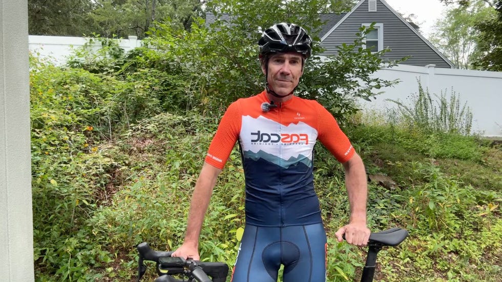 Cyclist in a jersey and helmet standing next to a bicycle in a natural setting. Cyclist in a jersey and helmet standing next to a bicycle in a natural setting.