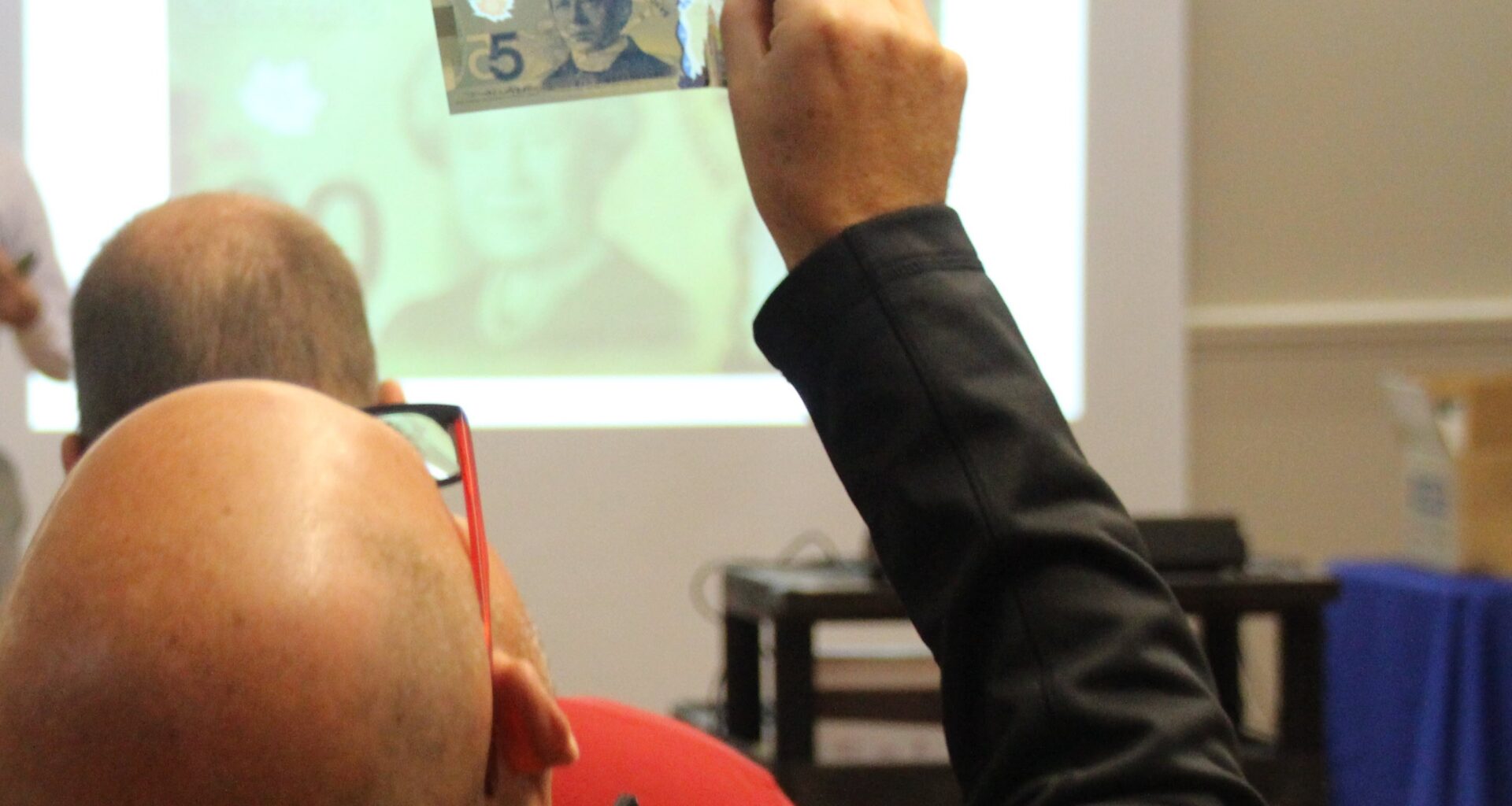 A man holds up a currency bill to check if it is counterfeit.