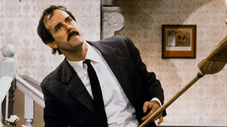 Basil Fawlty holding a broom in Fawlty Towers