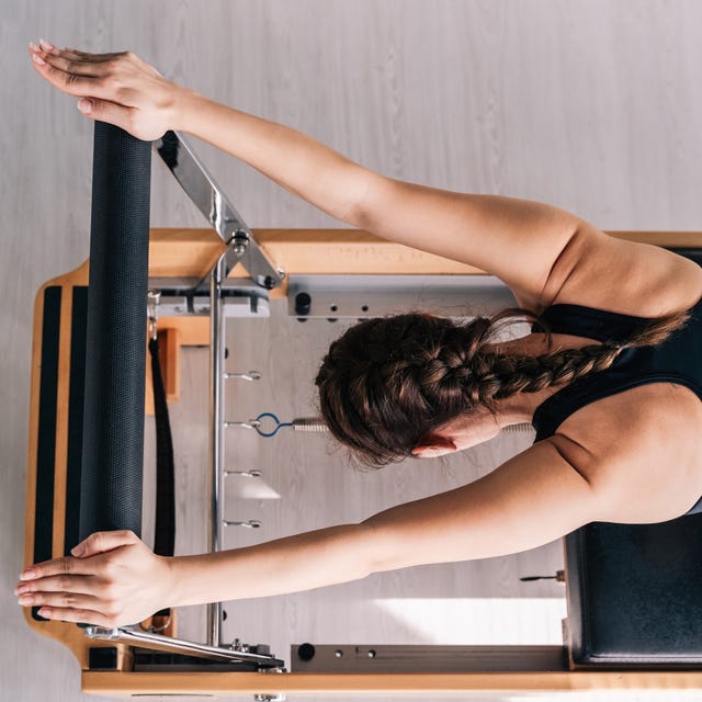 Slender beautiful woman doing Performer Pilates on exercise machines on a sunny day. Slender beautiful woman doing Performer Pilates on exercise machines on a sunny day.