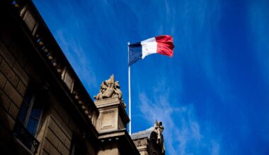 French tricolour flag (blue, white and red, symbol of the Republic of France) hanging from a flagpole above the entrance gate to the courtyard of the Elysee Palace, Exit from the Cabinet meeting at the Presidential Palace of the Elysee in Paris, France on August 27, 2025. The ministers get into their cars and leave the Elysee Palace. (Photo by Amaury Cornu / Hans Lucas via AFP)