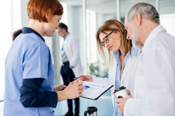 Medical professionals in discussion reviewing hospital reports in a bright clinical setting highlighting hidden hospital truths.