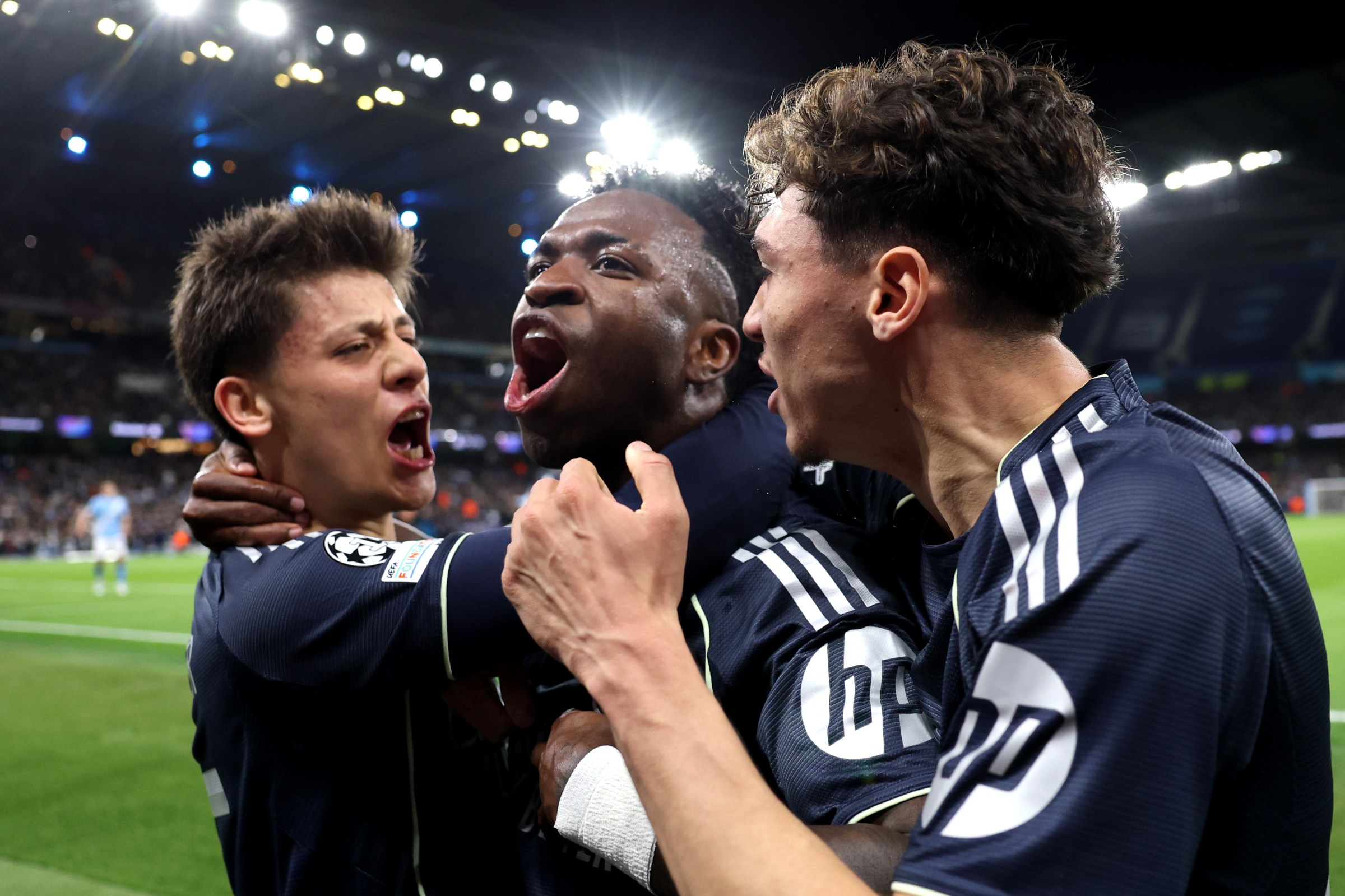 MANCHESTER, ENGLAND - MARCH 17: Vinicius Junior of Real Madrid celebrates scoring his team’s first goal from the penalty spot with teammates Arda Gueler and Thiago Pitarch during the UEFA Champions League 2025/26 Round of 16 Second Leg match between Manchester City FC and Real Madrid CF at City of Manchester Stadium on March 17, 2026 in Manchester, England. (Photo by Carl Recine/Getty Images)