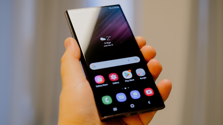 A person holding the Samsung Galaxy S22 Ultra in their palm