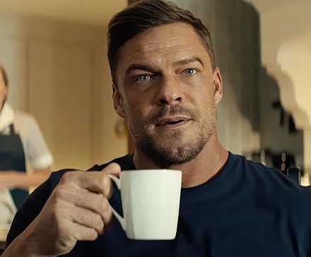 Alan Ritchson's Reacher holding a mug.