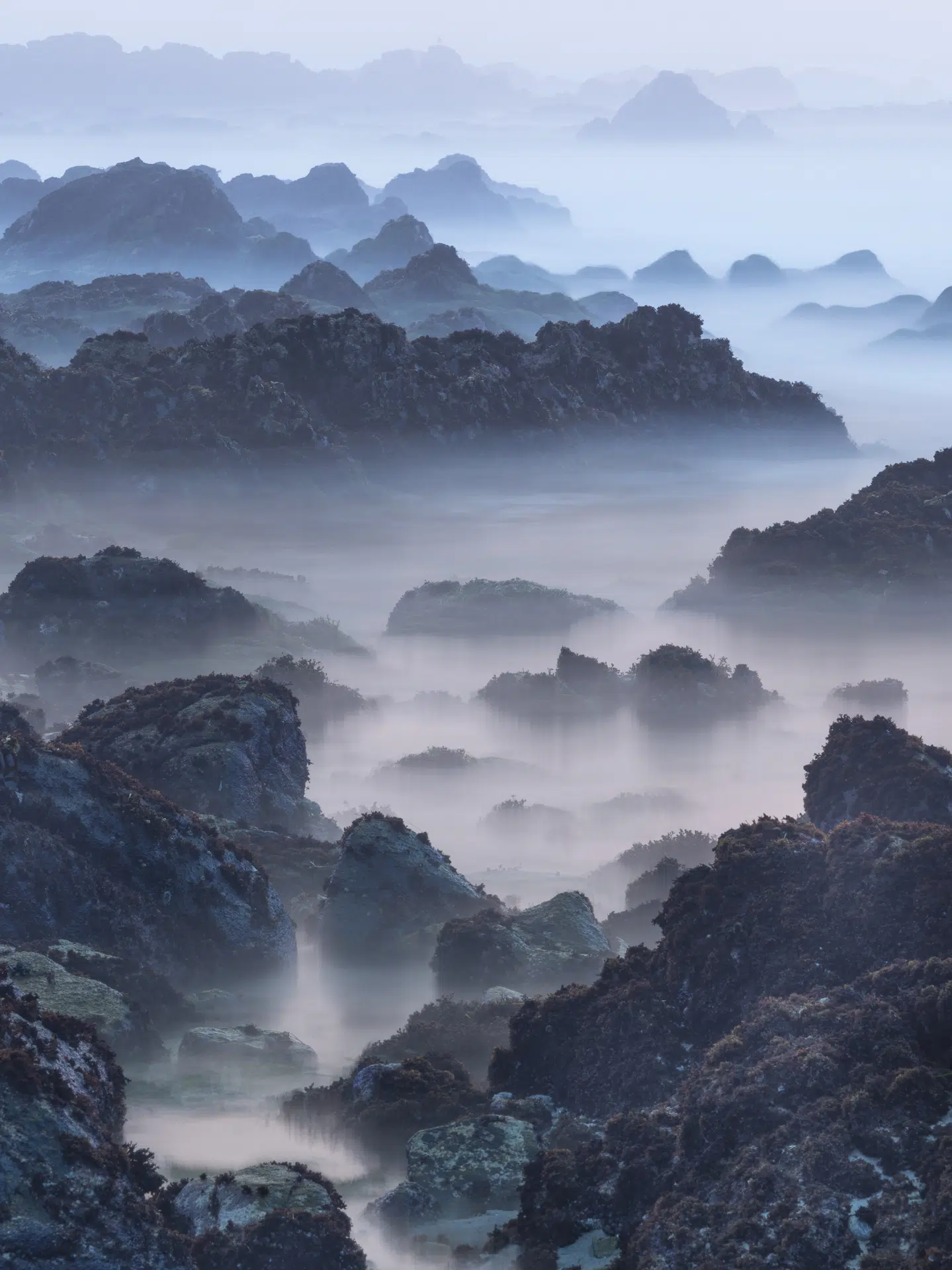 California, 2020. In the blue hush of twilight, the beach rocks of Northern California begin to resemble China’s karst mountains because light, scale, and erosion briefly align.