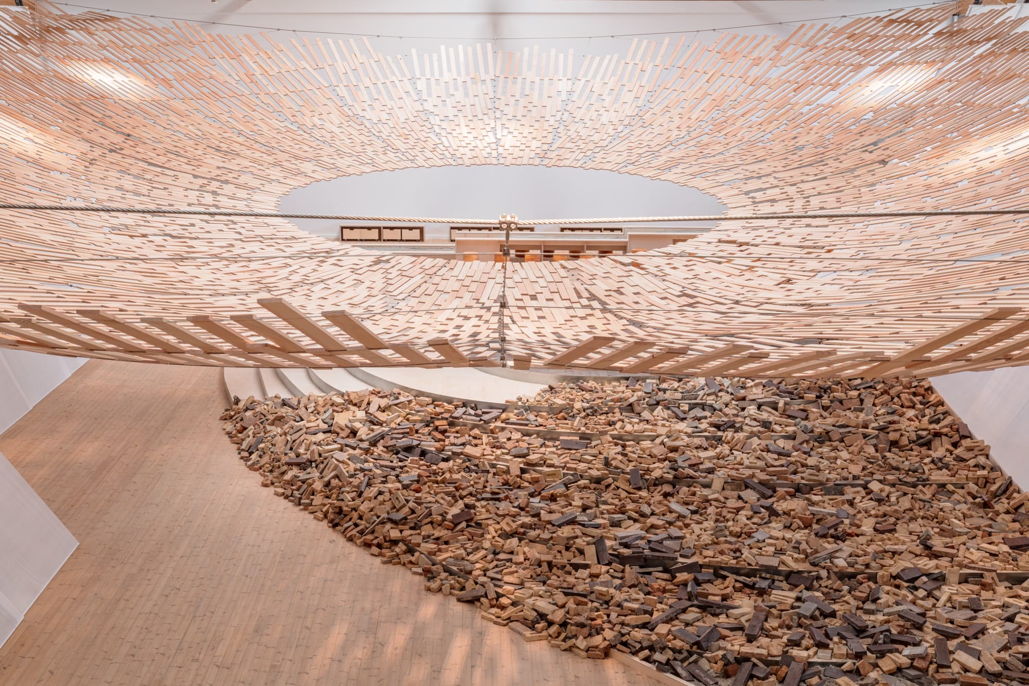 light streams through a wooden canopy in a large scale installation of wood and brick by Kengo Kuma