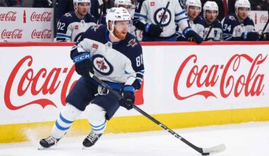 Kyle Connor #81 of the Winnipeg Jets skating with the puck, subject of significant NHL offseason trade rumors, against boards with Coca-Cola logos.