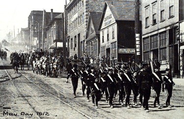 May Day, 1912: Cadets march down the 8th Street, between Carnarvon and Columbia. They are followed by a horse-drawn carriage that probably carries the May Queen and her court. Note the streetcar tracks.