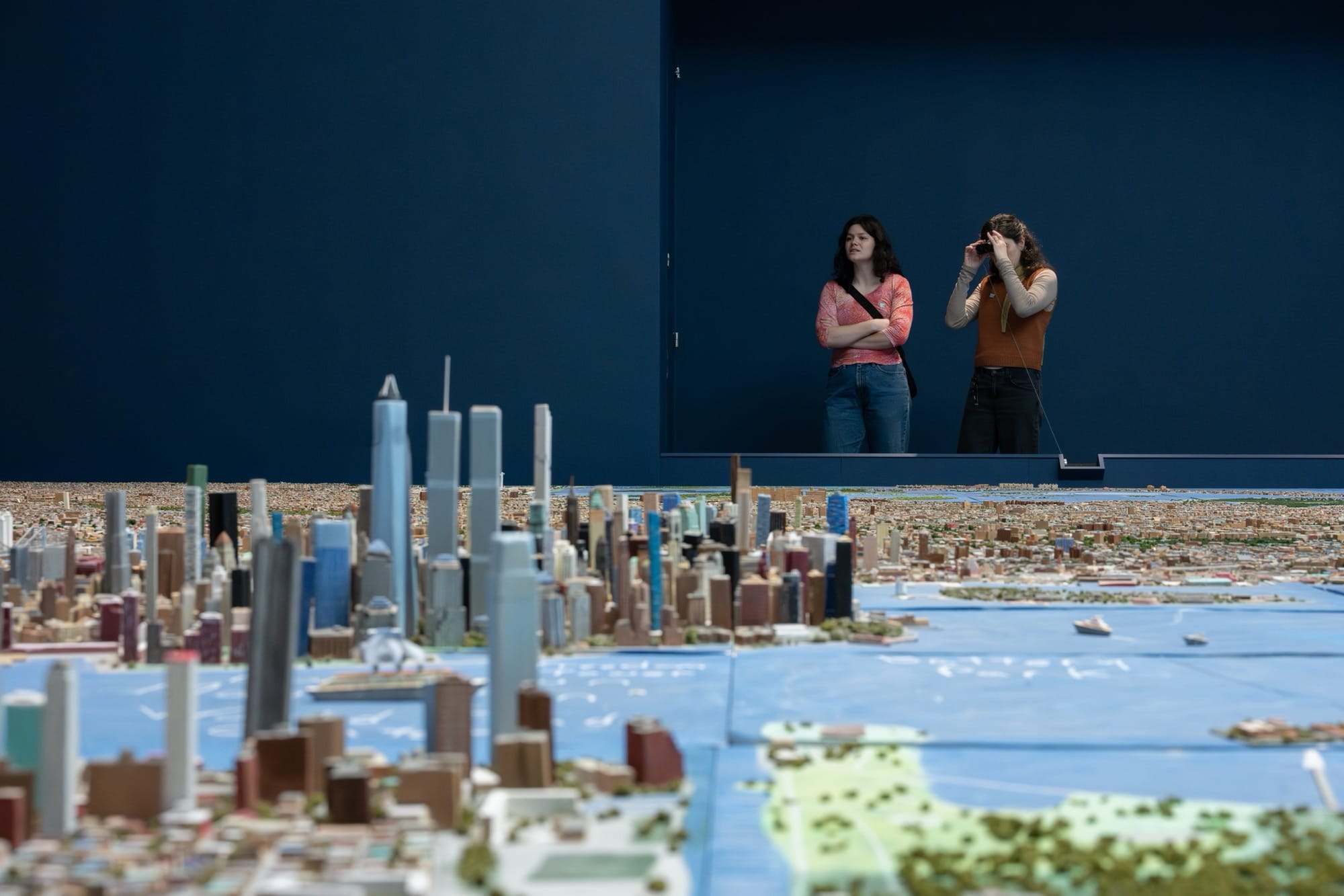 visitors to the Museum of New York look over an expansive handmade model of the city