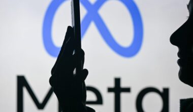 An image of a woman holding a cell phone in front of the Meta logo displayed on a computer screen.