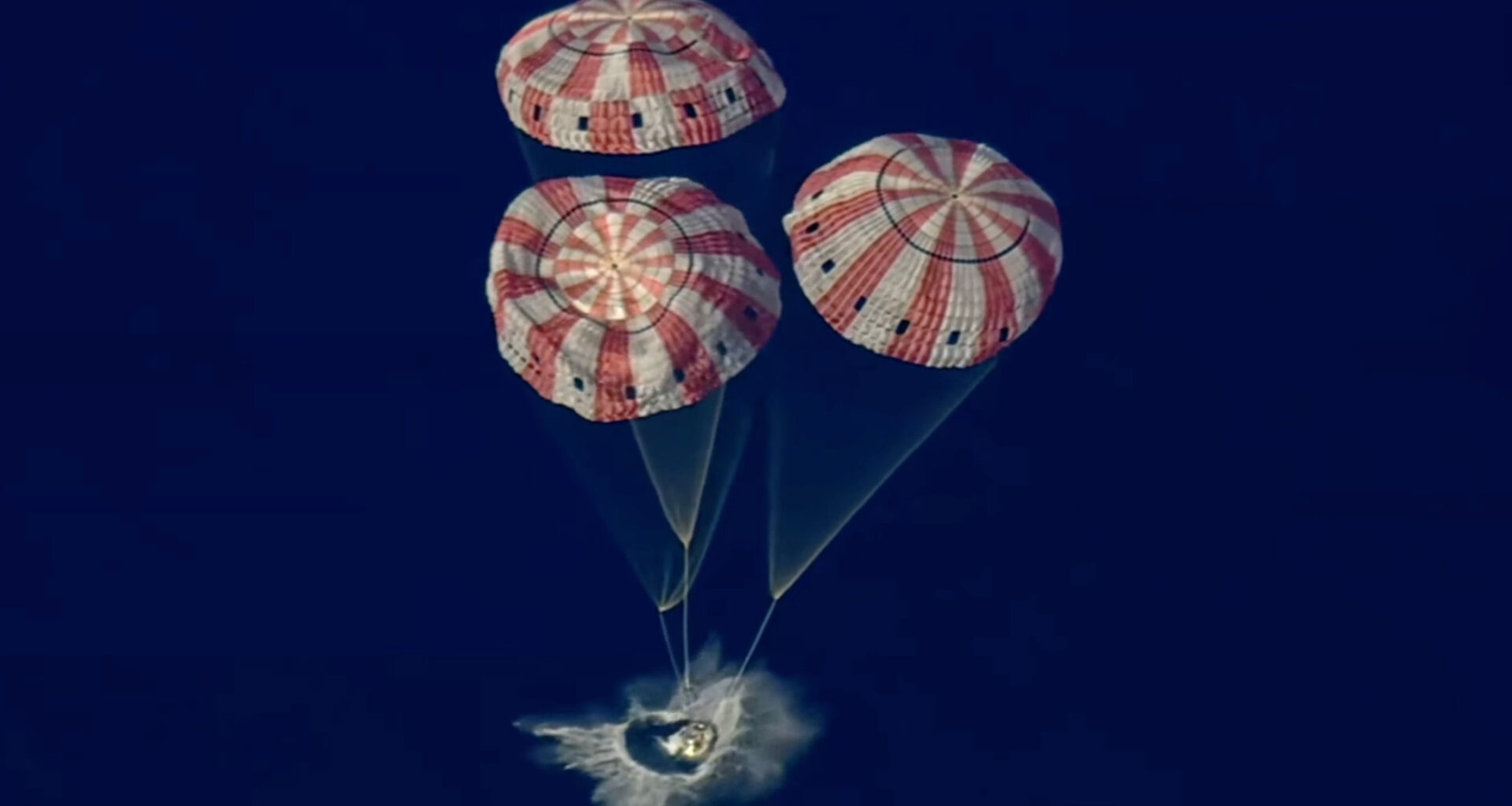 A space capsule splashes down in the ocen.
