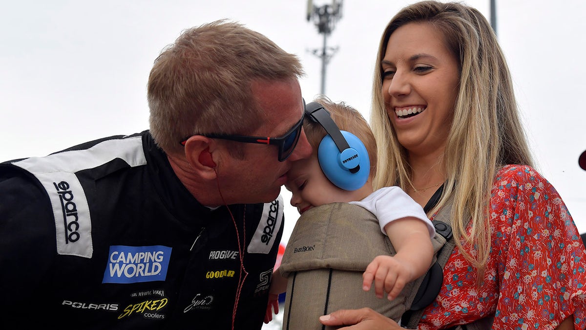 Greg Biffle kisses his son with Cristina Grossu looking on at Slinger Speedway