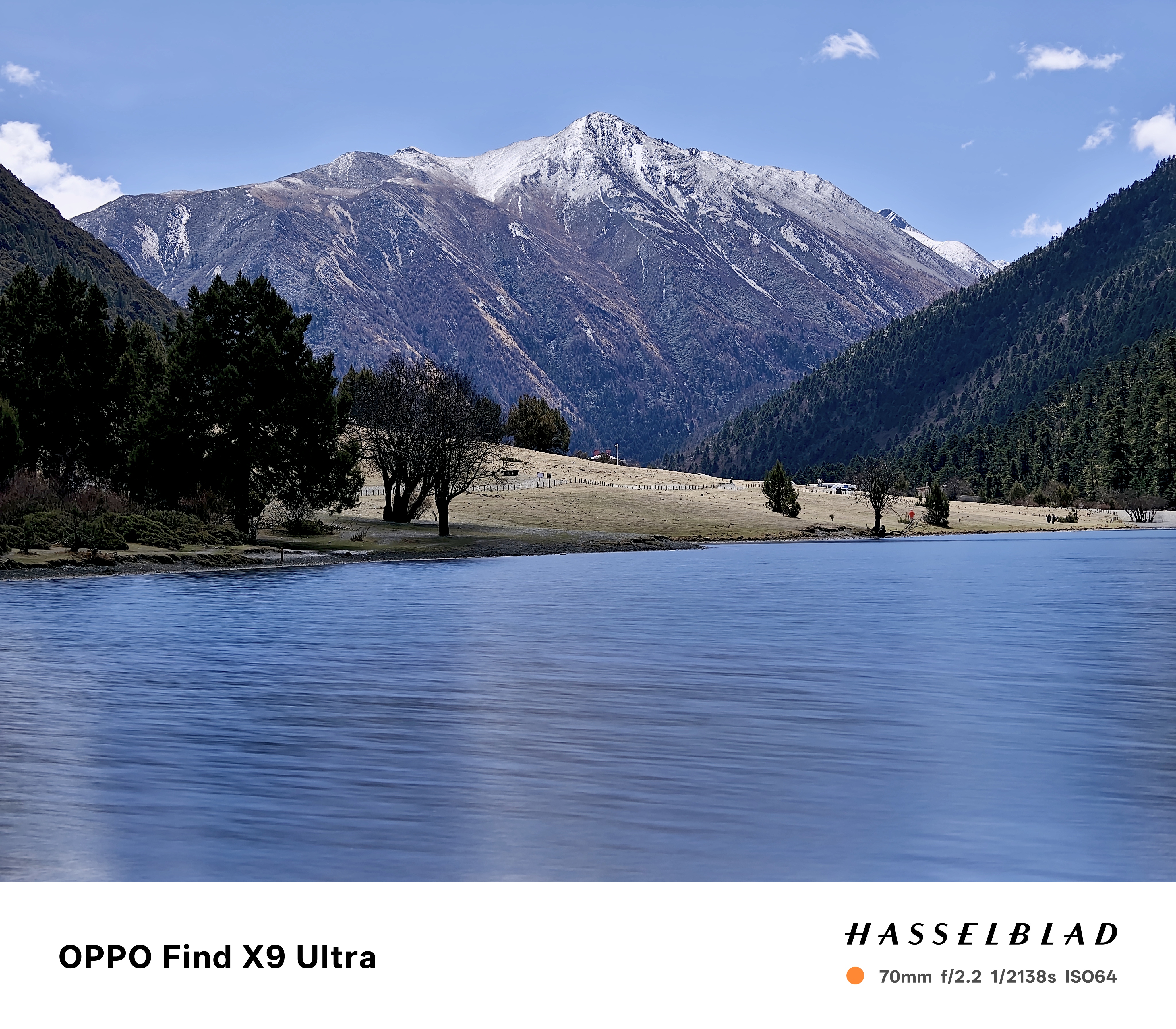 A snowy mountain by a lake, the water is blurred