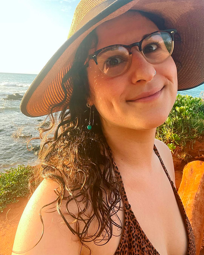Woman wearing glasses and a sunhat near the ocean, related to OpenAI CEO Sam Altman lawsuit news.