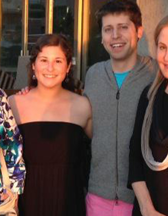 OpenAI CEO Sam Altman smiling with family members in a casual group photo outdoors during daytime.