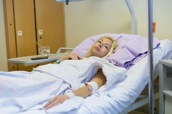 Patient resting in hospital bed with IV line, illustrating surgical staff experiences with unhinged sedation confessions.