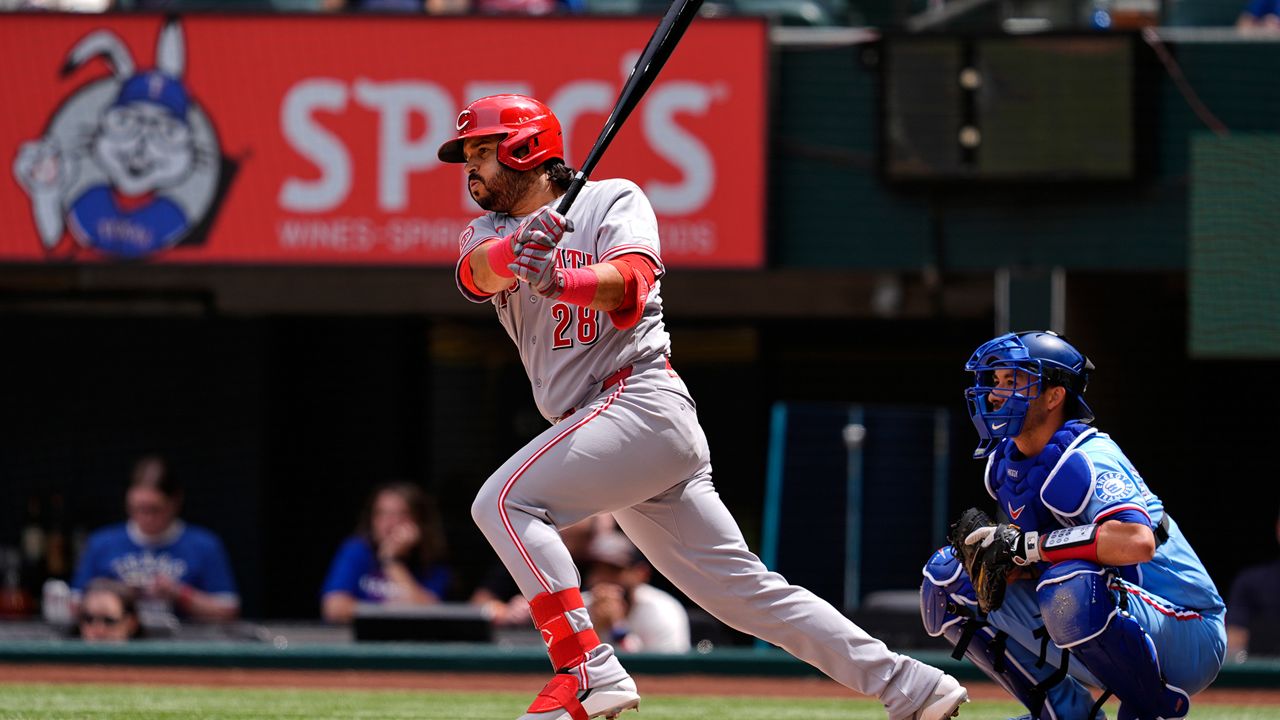 Cincinnati Reds' Eugenio Suarez (28) follows through on a run-scoring single as Texas Rangers' Kyle Higashioka (11) looks on in the fourth inning of a baseball game Sunday, April 5, 2026, in Arlington, Texas. (AP Photo/Tony Gutierrez)