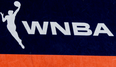 WNBA logo with a silhouette of a female basketball player in action, set against a dark blue and orange background.