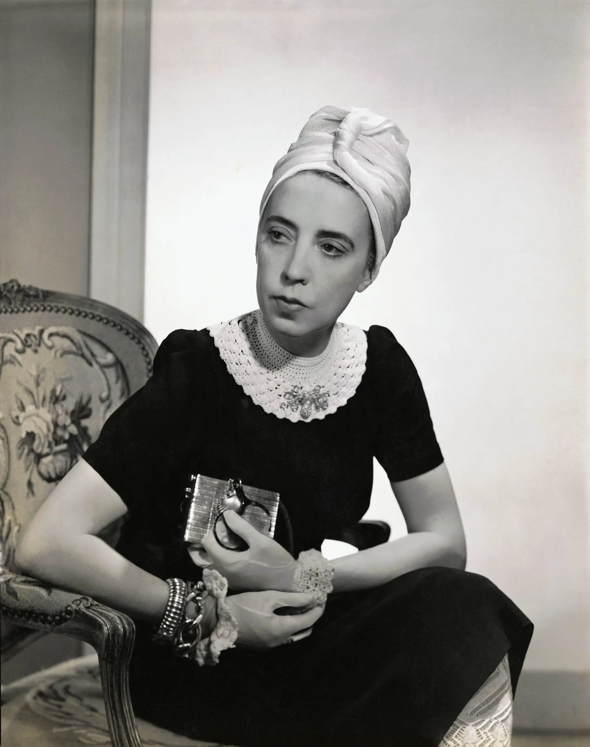Designer Elsa Schiaparelli wearing black silk dress with crocheted collar of her own design and a tuban, as featured in Vogue in 1940