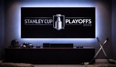 Home theater scene with a large TV displaying the Stanley Cup Playoffs 2026 logo, blue ambient light, and hockey gear on a cabinet beneath.
