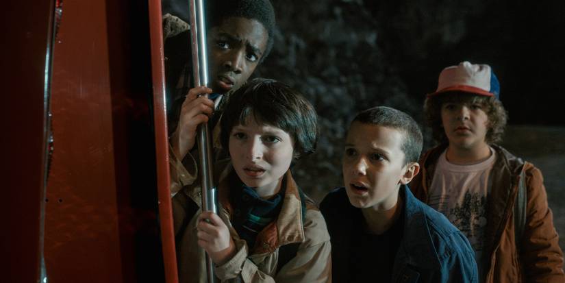 Lucas Sinclair (Caleb McLaughlin), Mike Wheeler (Finn Wolfhard), Eleven (Millie Bobby Brown), and Dustin Henderson (Gaten Matarazzo) hide in the first season of 'Stranger Things'