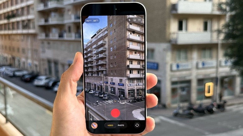 A hand holding an iPhone with the camera app opened