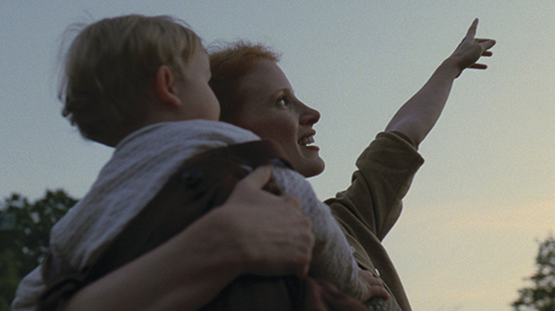 Jessica Chastain as Mrs. O'Brien in The Tree of Life, holding a child and pointing up to the sky.