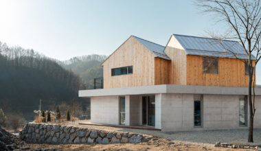 this home in korea is shaped by twin timber gables atop a concrete base