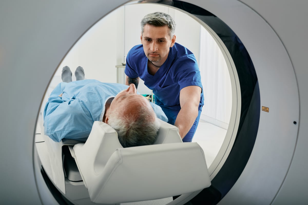 Medical professional assisting a person in an MRI machine.
