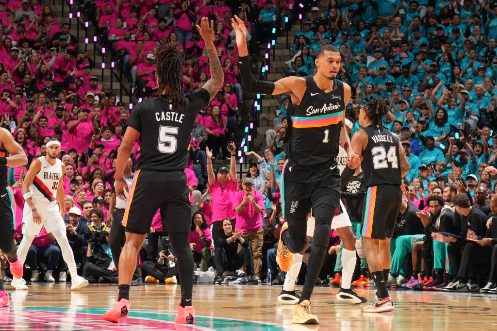 Stephon Castle and Victor Wembanyama high-five during a game.