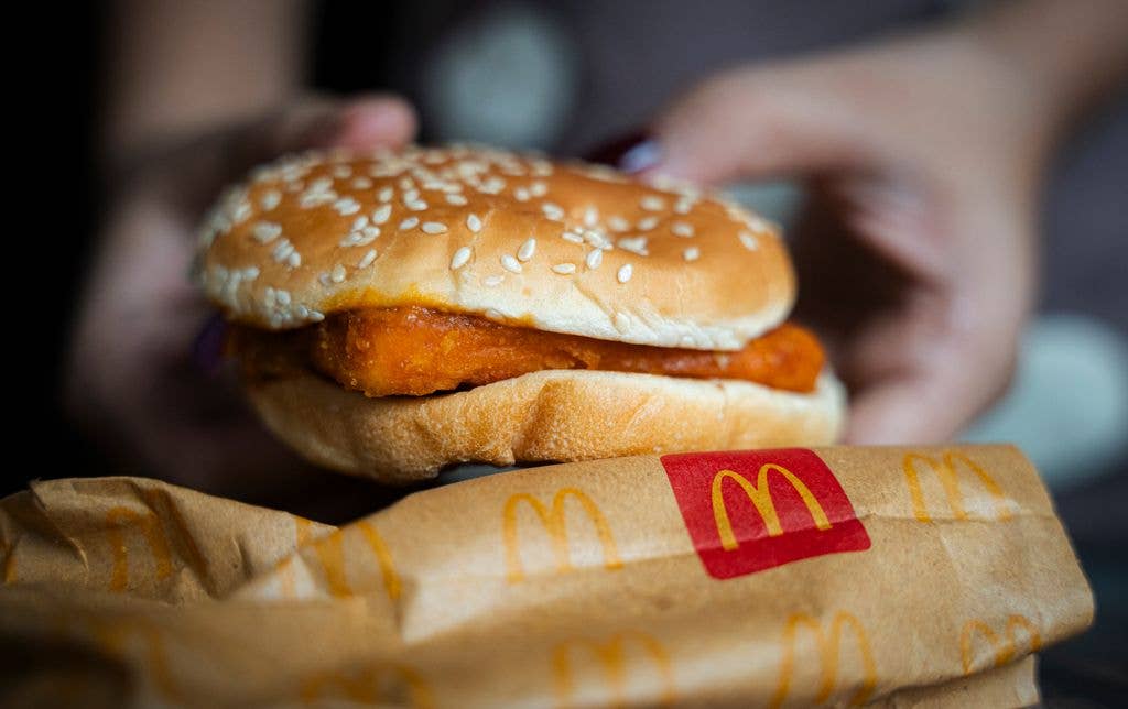 A woman shows a McDonald's burger in Guwahati, India, on October 26, 2024. McDonald's recent food safety issues cause a 5% stock drop after E. coli contamination in the United States.