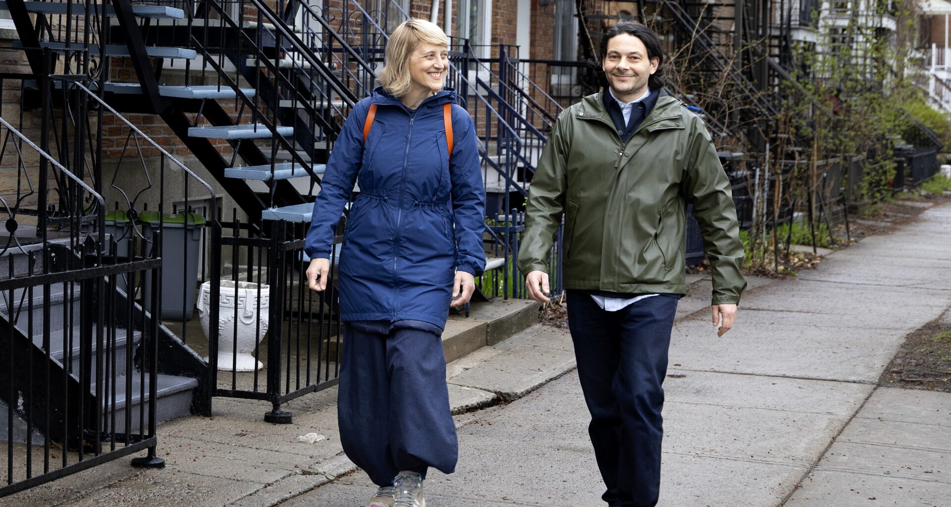 A man an d a woman walk along the sidewalk.