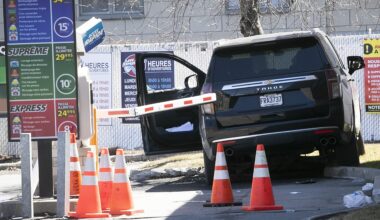 An SUV is behind orange safety cones at a car wash. The door is open and the SUV is partially over a curb.