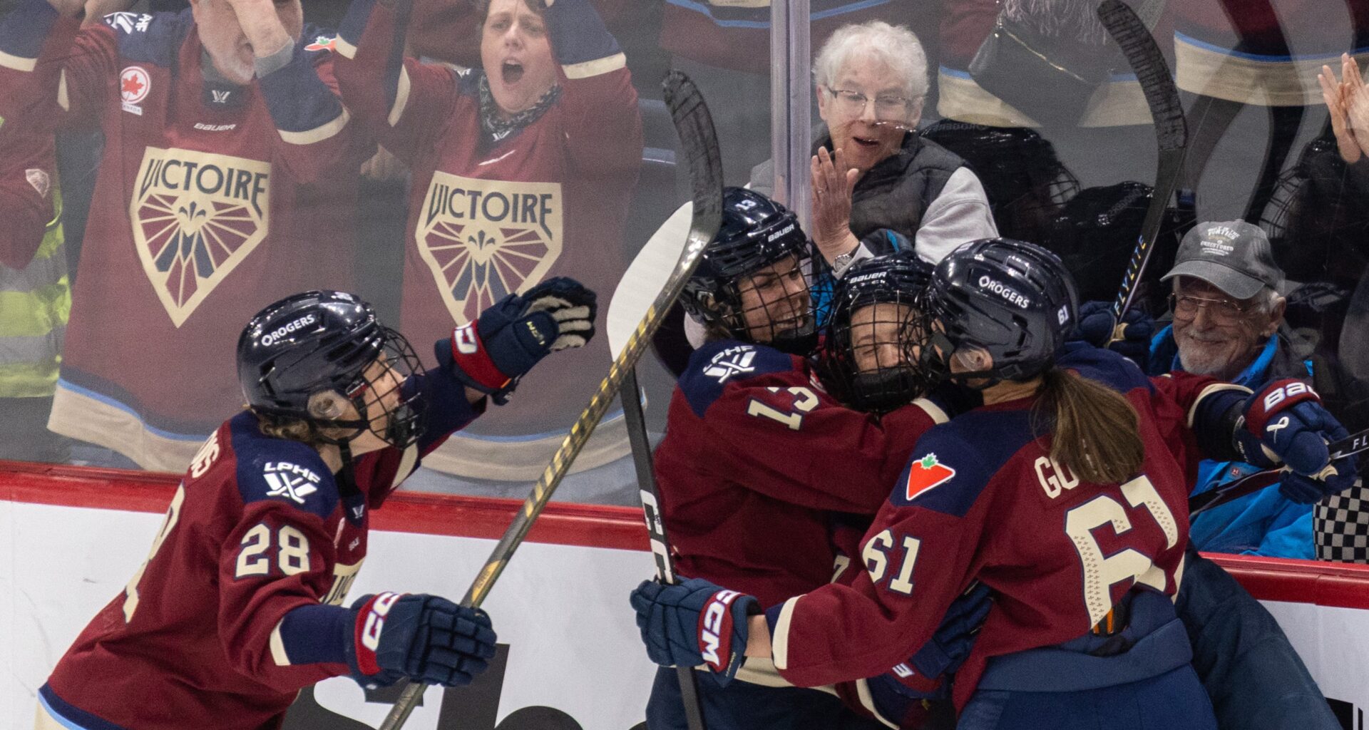 Montreal Victoire players embrace in celebration on the ice.