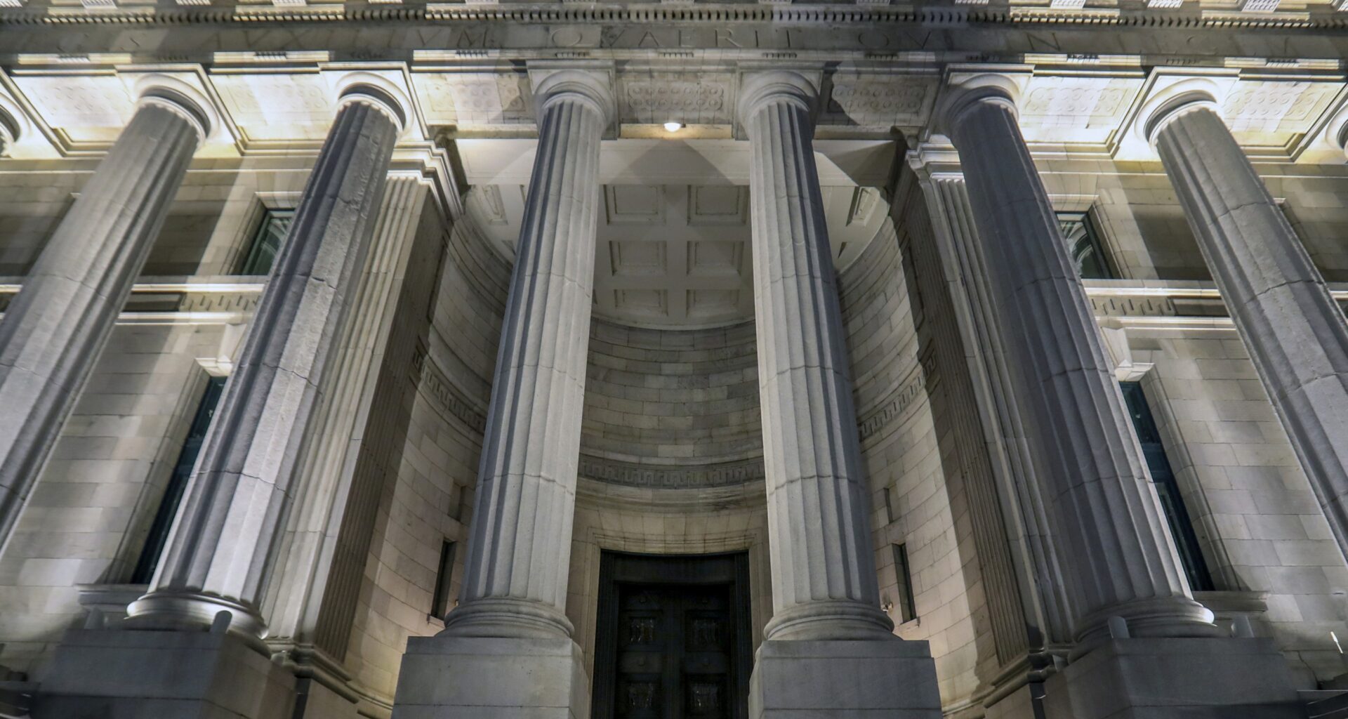 Brightly lit columns in front of a large building at night.