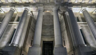 Brightly lit columns in front of a large building at night.