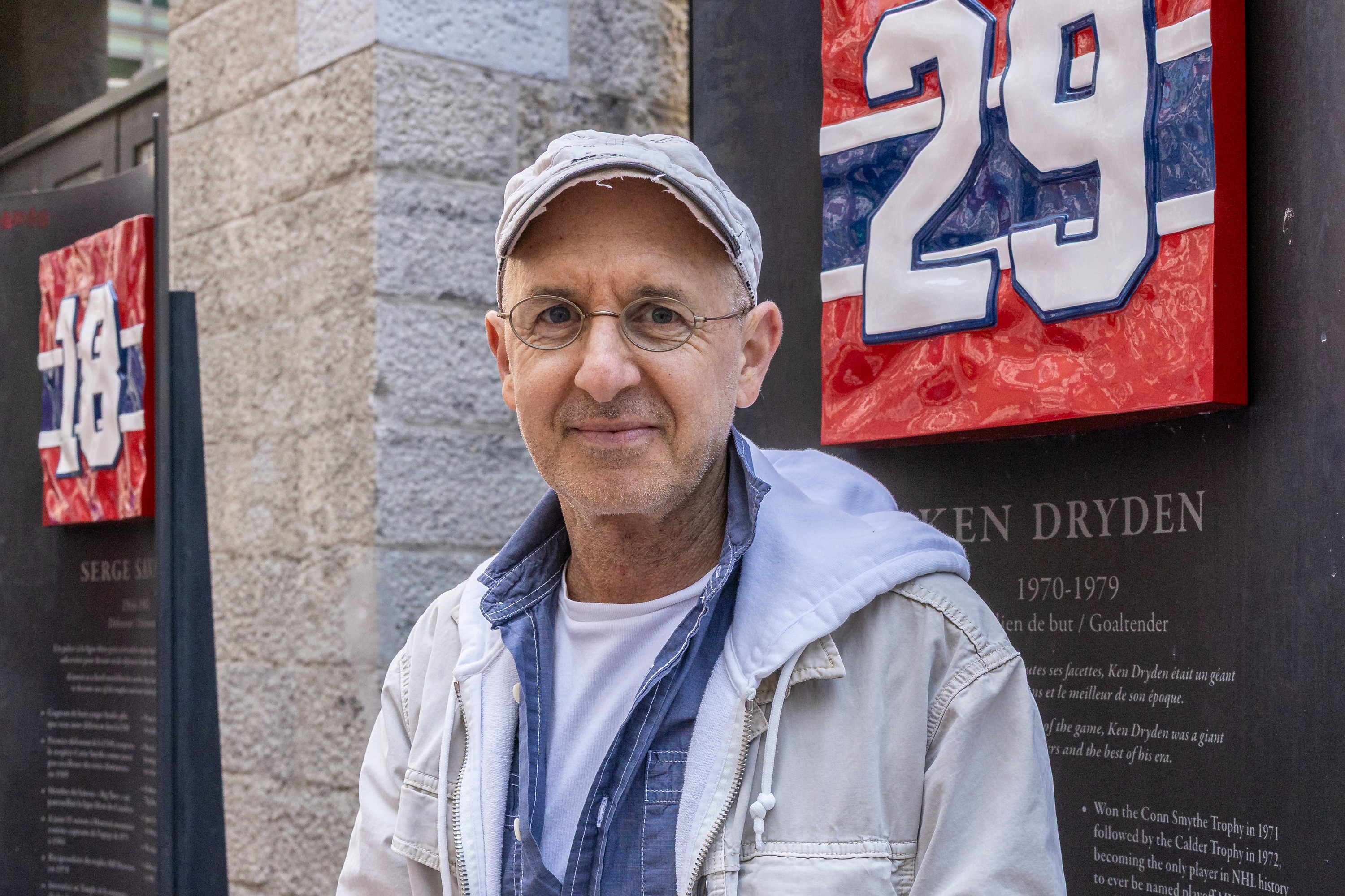 Oren Safdie stands in front of a plaque about Ken Dryden outside.