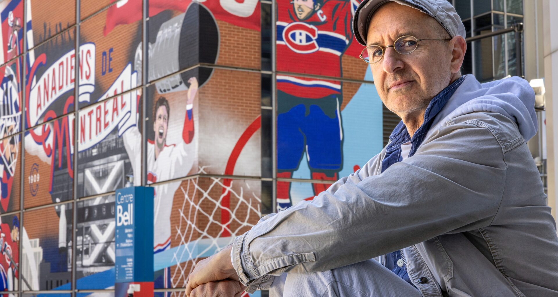 Oren Safdie sits outside with a Bell Centre mural of Canadiens players in the background.