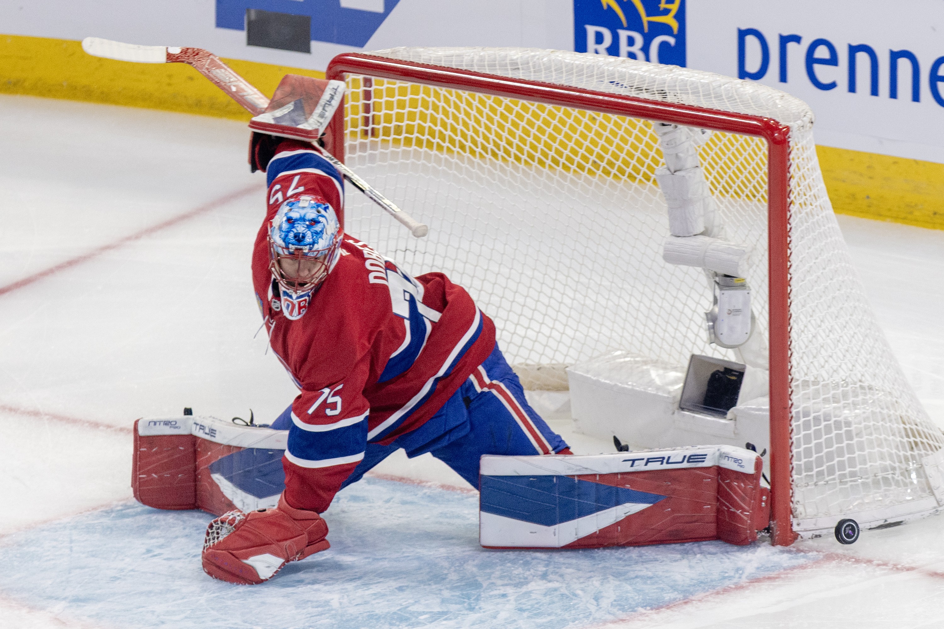 Hockey goaltender kicks the puck wide after a shot.
