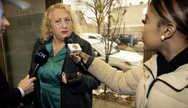 A woman is confronted by two journalists holding microphones.
