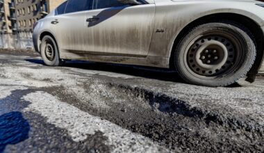 Car drives by big pothole on Montreal road.