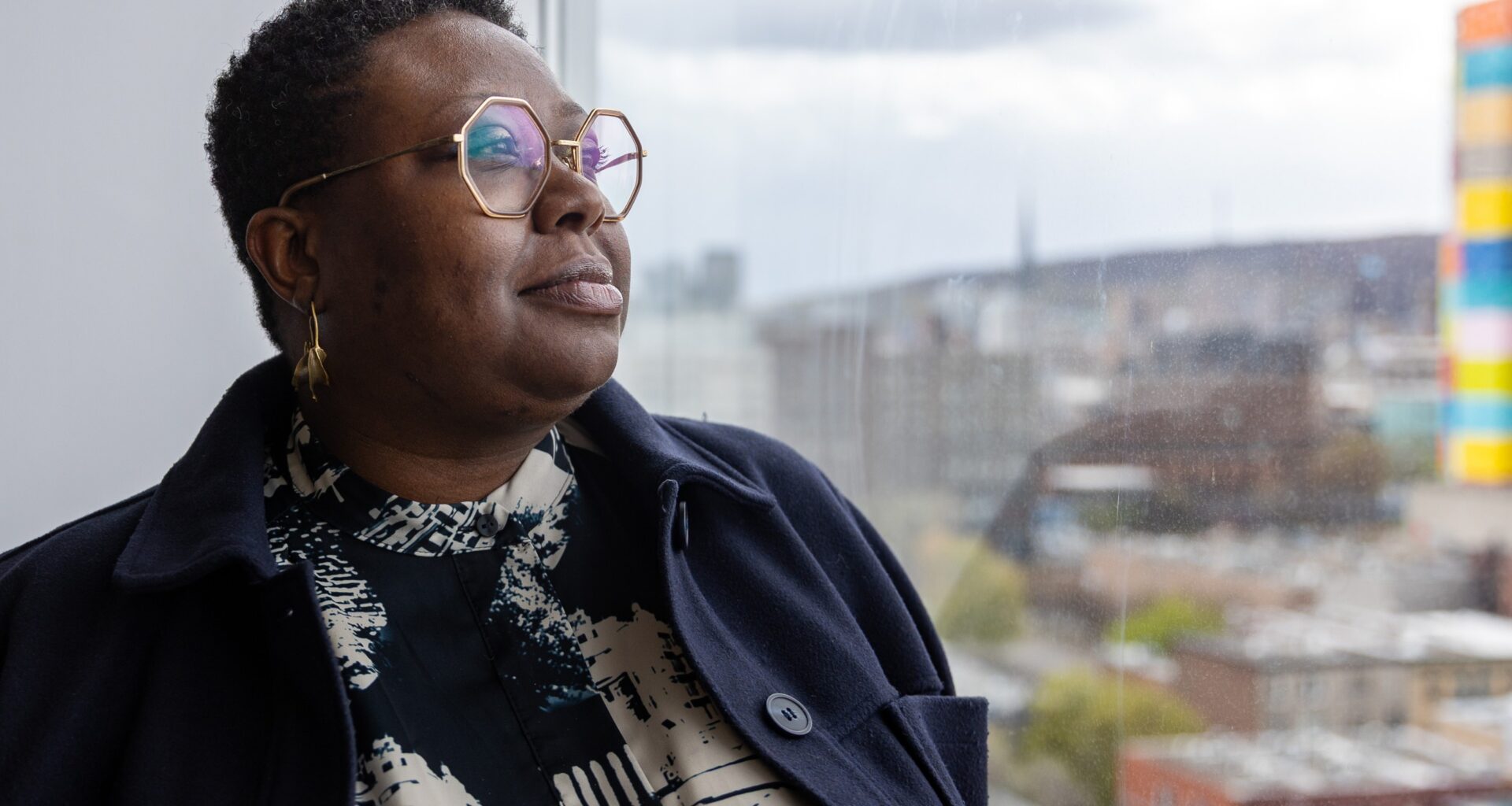 Ericka Alneus looks out a window facing the city.