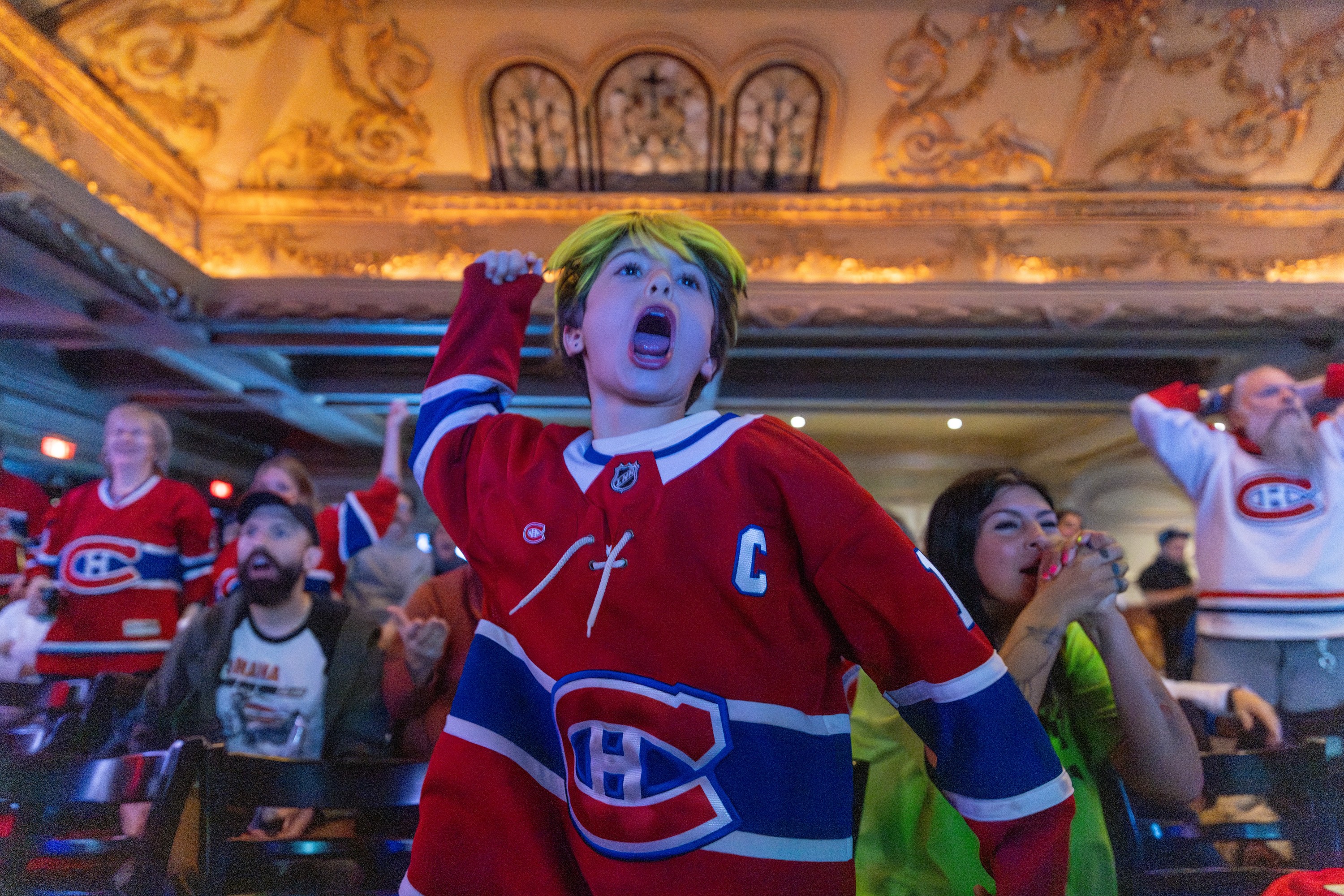A young Habs fan fist pumps in front of a crowd to celebrate a goal. 